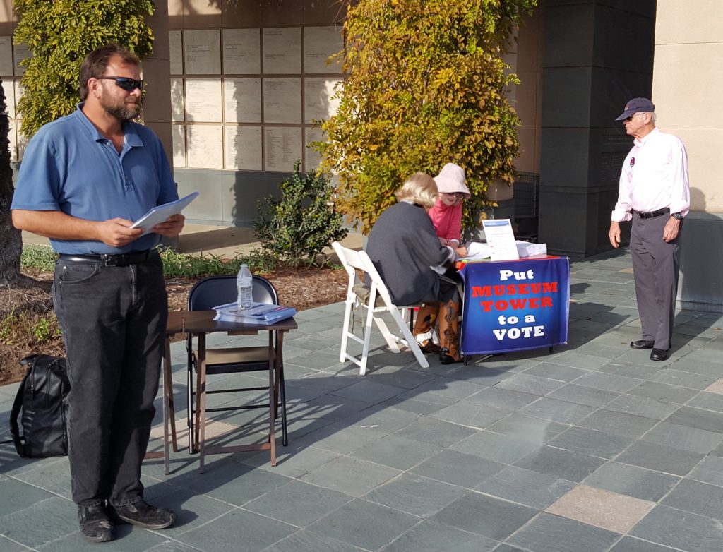 A representative of OCMA Urban Housing, LLC (left) passes out "Petition Hurts Our Kids" flyer near the Line in the Sand petition table in front of the Newport Beach Public Library